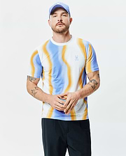 Mens Blaze Sport Tee, a slim fit performance jersey t-shirt featuring a vibrant white, blue, and orange swirling wave pattern with a small embroidered Psycho Bunny skull logo on the left chest.