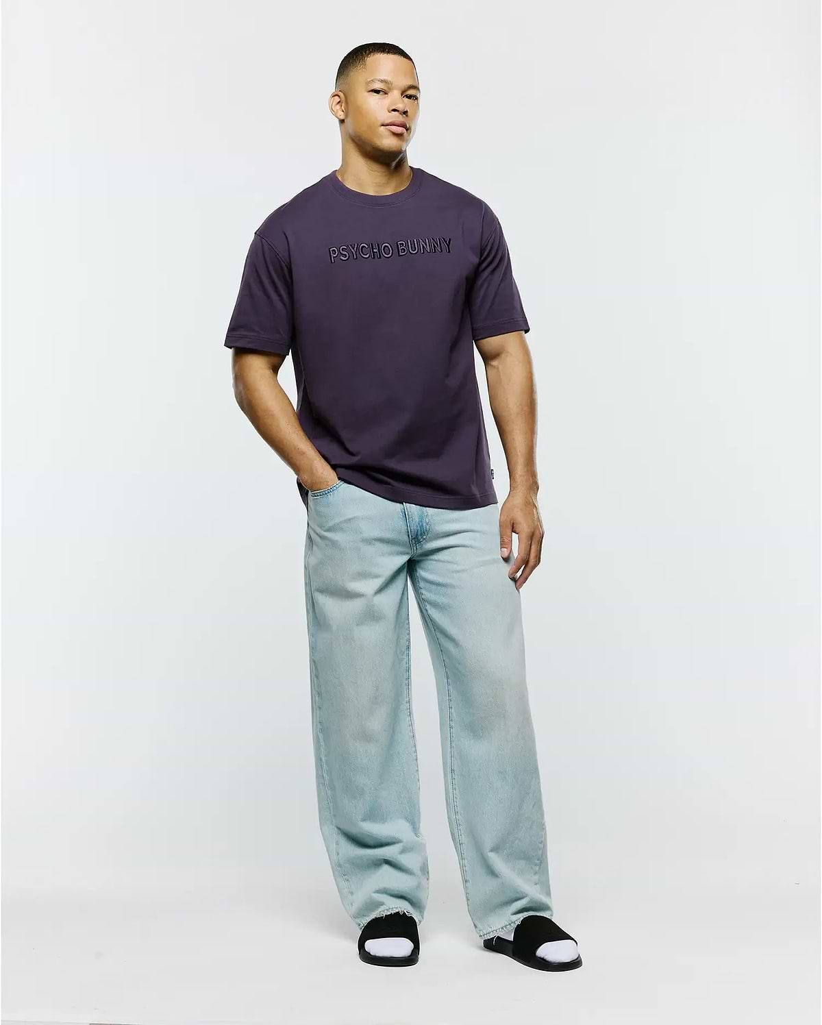 Mens Windcrest Relaxed Fit Tee in deep plum, crafted from smooth jersey knit fabric, featuring a prominent, tonal PSYCHO BUNNY text logo centered on the chest.
