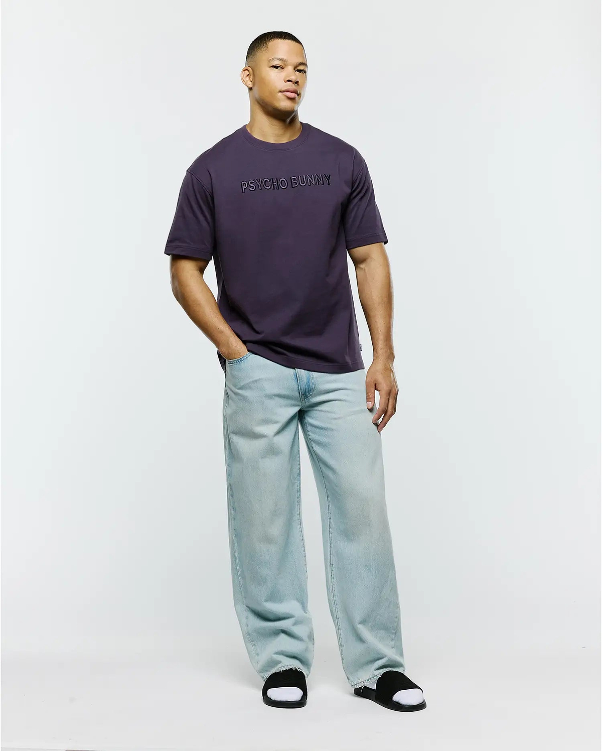Mens Windcrest Relaxed Fit Tee in deep plum, crafted from smooth jersey knit fabric, featuring a prominent, tonal PSYCHO BUNNY text logo centered on the chest.