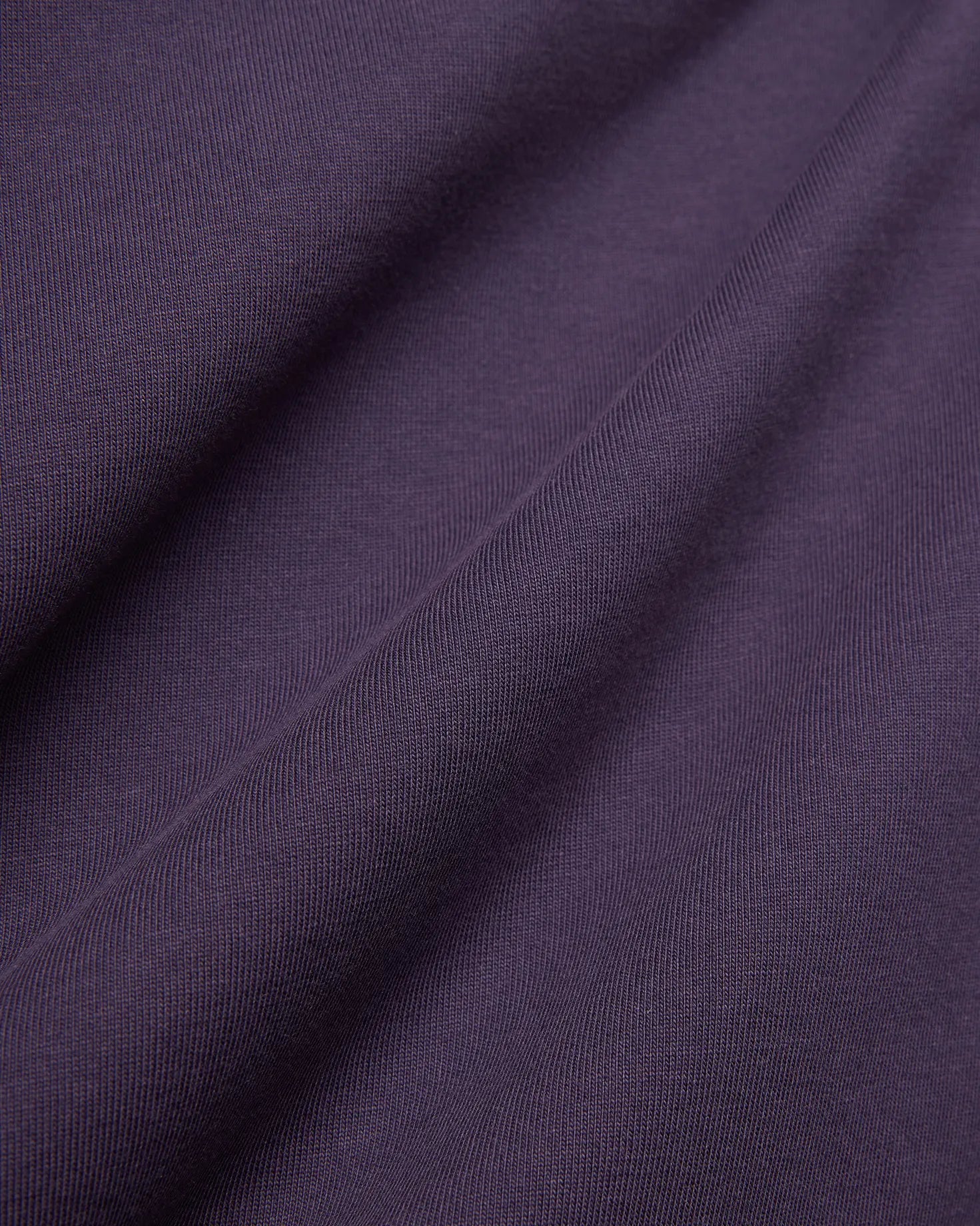 Dark Purple Mens Windcrest Relaxed Fit Tee fabric, featuring a soft, finely ribbed jersey knit texture with subtle vertical lines and gentle folds.