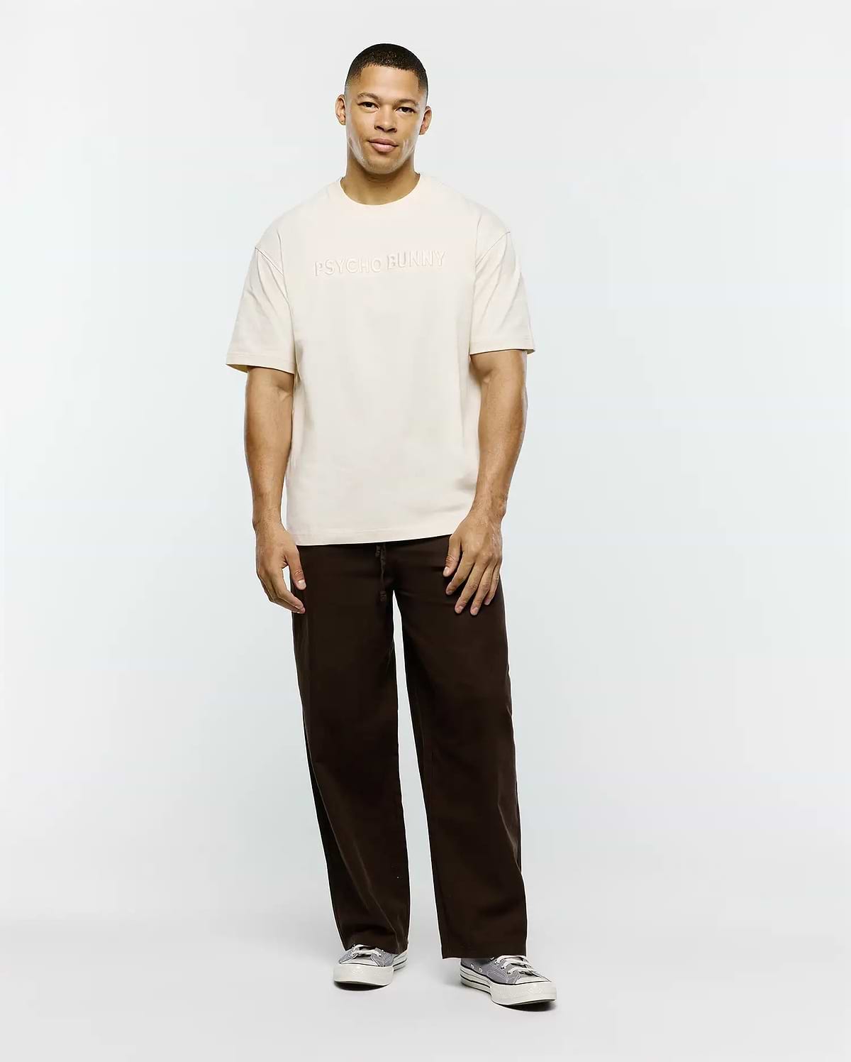 Mens Windcrest Relaxed Fit Tee in cream, crafted from soft jersey, featuring a prominent, tone-on-tone embossed PSYCHO BUNNY text logo centered on the chest. (4)