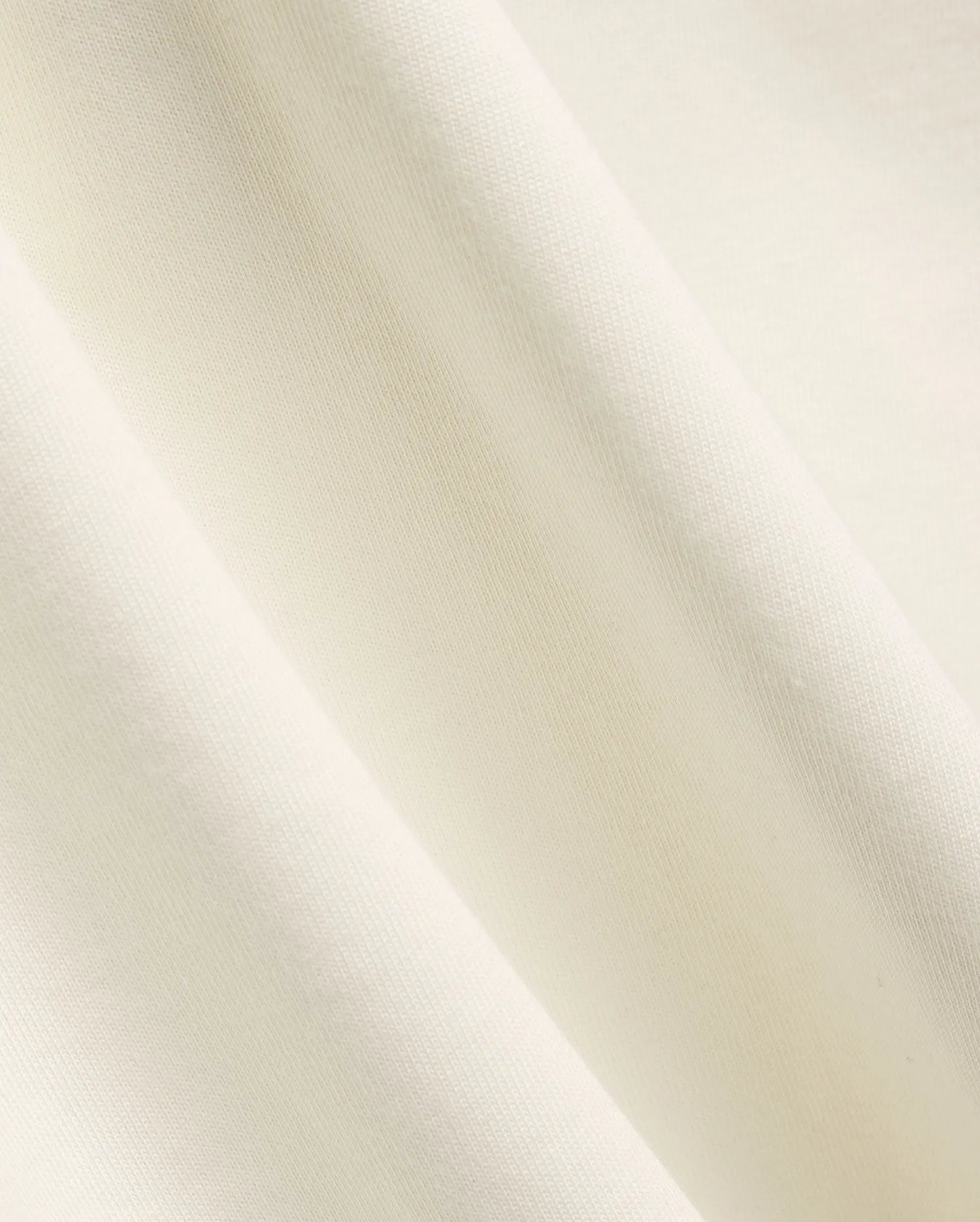 Mens Windcrest Relaxed Fit Tee in a soft, creamy off-white hue, showcasing its premium, smooth fine jersey knit fabric texture with elegant, flowing diagonal folds. (6)
