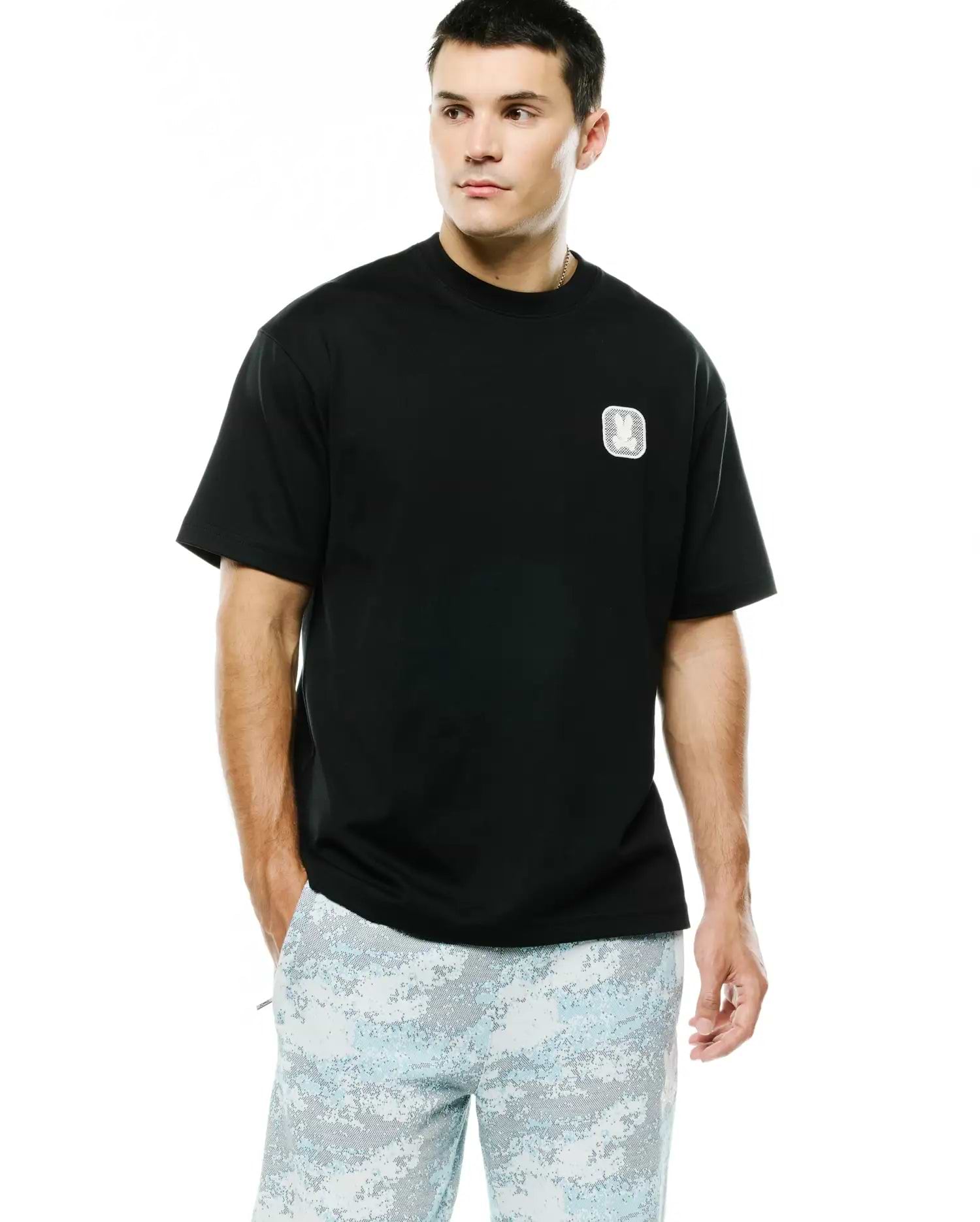 Men's Samson Oversized Bunny Tee in black jersey knit, featuring an embroidered white and silver Psycho Bunny skull logo on a textured square patch on the left chest. (1)