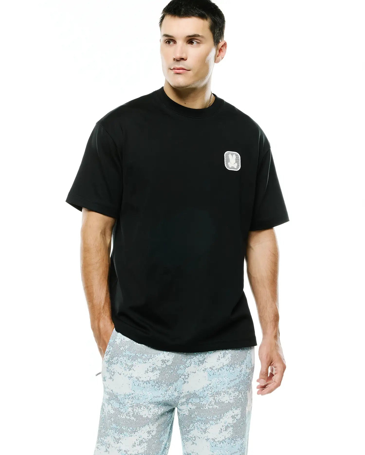 Men's Samson Oversized Bunny Tee in black jersey knit, featuring an embroidered white and silver Psycho Bunny skull logo on a textured square patch on the left chest. (1)