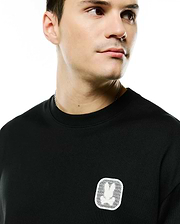 Men's Samson Oversized Bunny Tee in black jersey knit, featuring a small white embroidered Psycho Bunny skull logo patch with a mesh background on the left chest. (2)