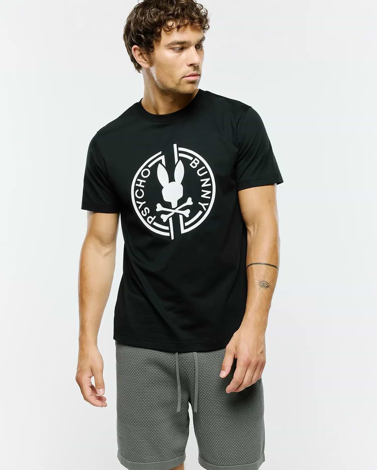 Mens Santa Fe Bunny Graphic Tee, a classic fit black jersey knit t-shirt featuring a large white Psycho Bunny skull and crossbones logo graphic encircled by Psycho Bunny text on the chest.