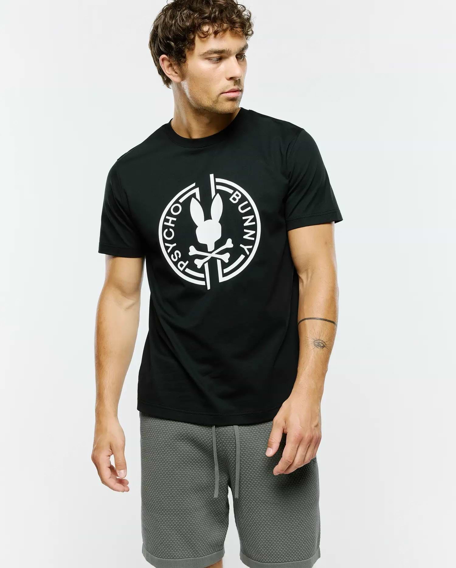 Mens Santa Fe Bunny Graphic Tee, a classic fit black jersey knit t-shirt featuring a large white Psycho Bunny skull and crossbones logo graphic encircled by Psycho Bunny text on the chest.
