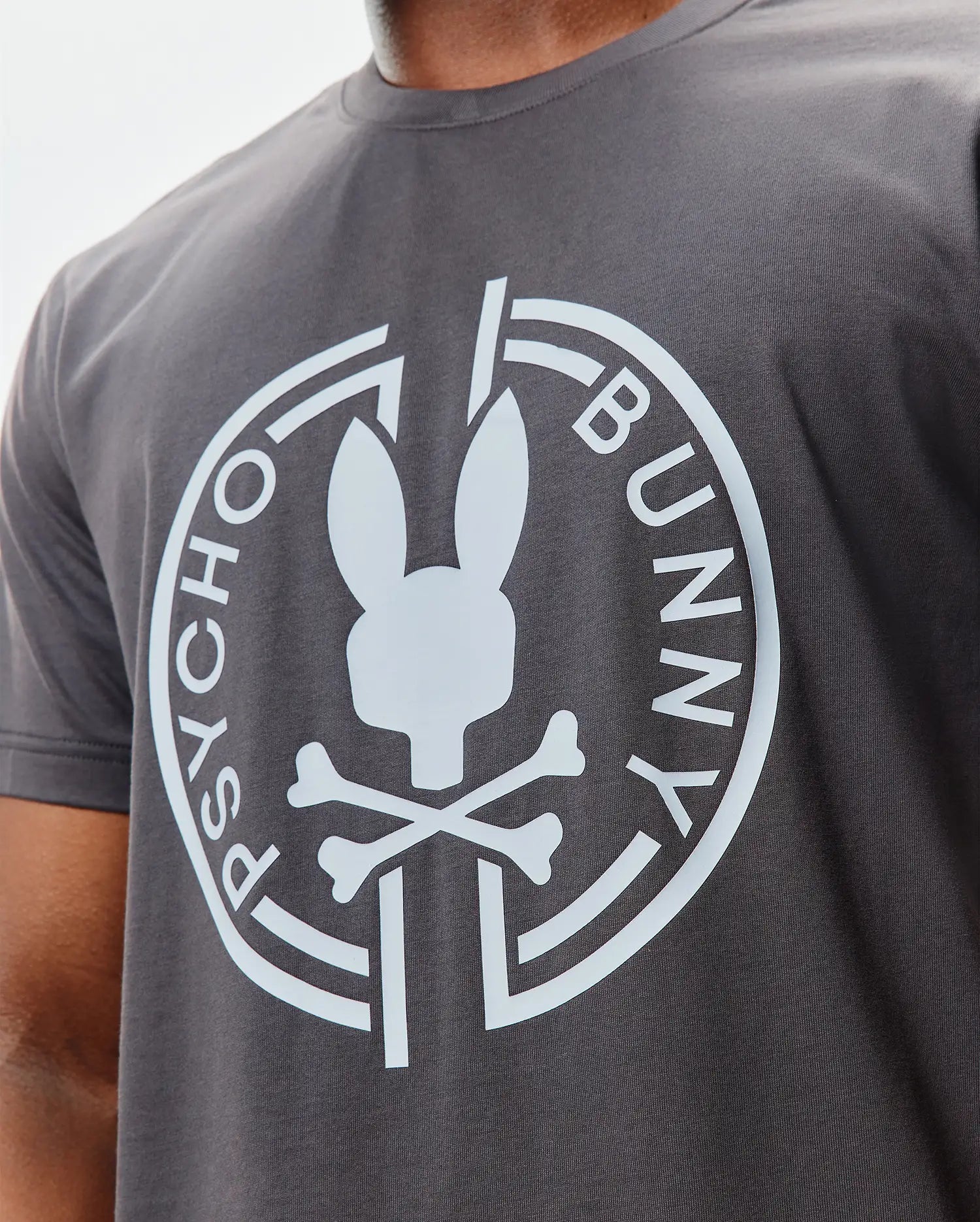 Mens Santa Fe Bunny Graphic Tee, a dark grey classic fit jersey t-shirt featuring a large white Psycho Bunny skull and crossbones logo with circular text on the chest. (3)