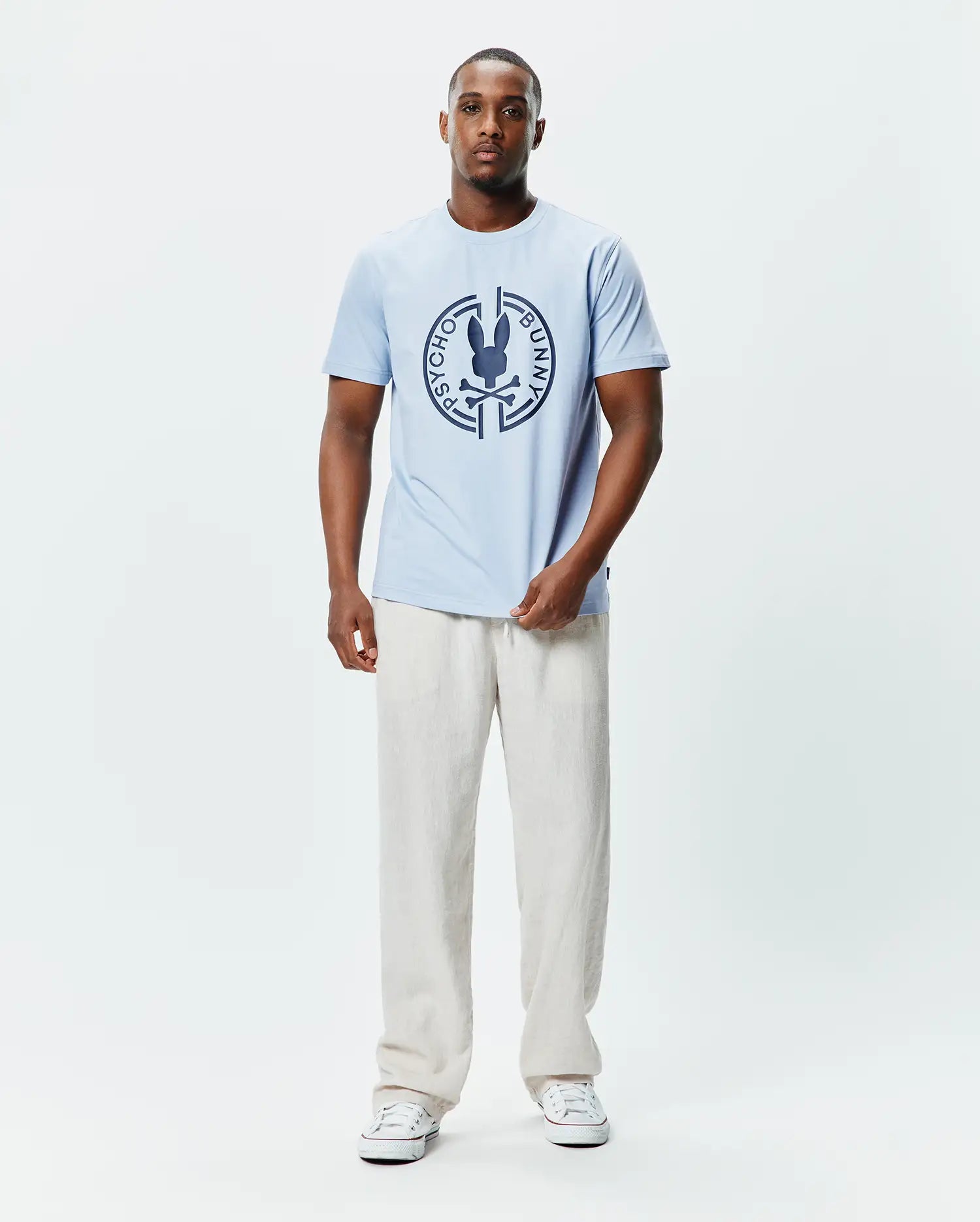 Mens Santa Fe Bunny Graphic Tee, a light blue classic fit jersey t-shirt featuring a large dark blue circular chest graphic with the iconic Psycho Bunny skull and crossbones logo. (4)