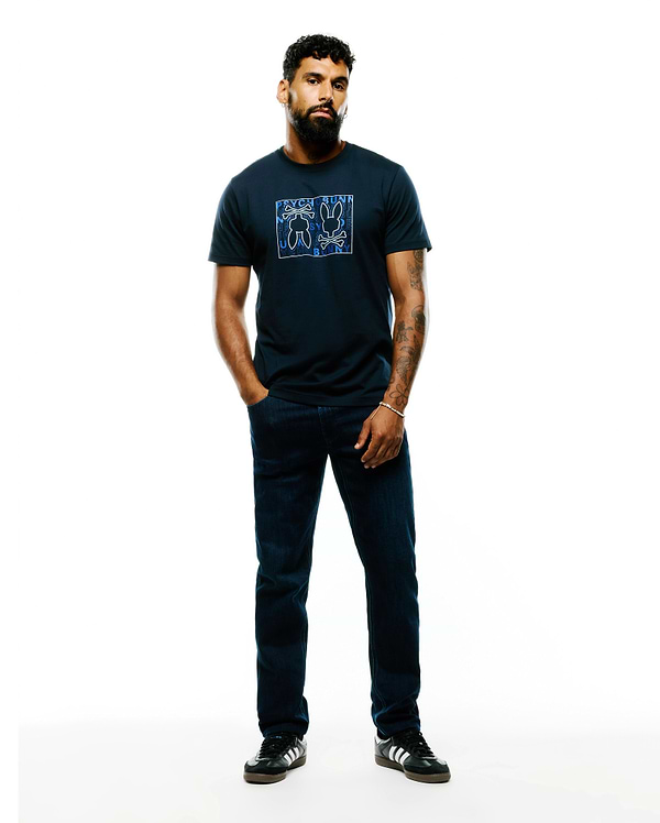 Mens Gold Coast Pima Cotton Graphic Tee, a navy classic fit Pima cotton jersey t-shirt with a large blue and white outlined Psycho Bunny skull, ears, and text graphic on the chest.