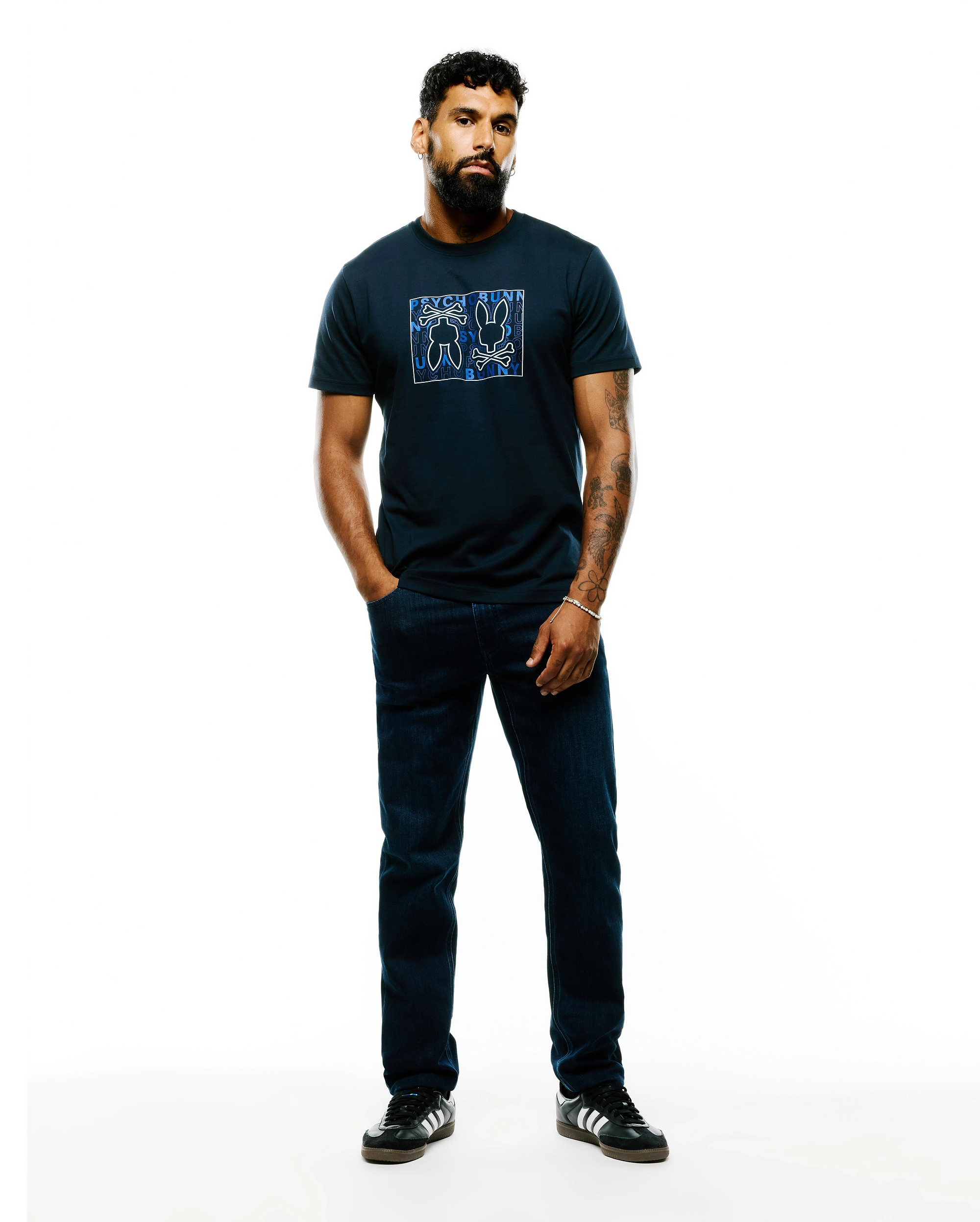 Mens Gold Coast Pima Cotton Graphic Tee, a navy classic fit Pima cotton jersey t-shirt with a large blue and white outlined Psycho Bunny skull, ears, and text graphic on the chest.