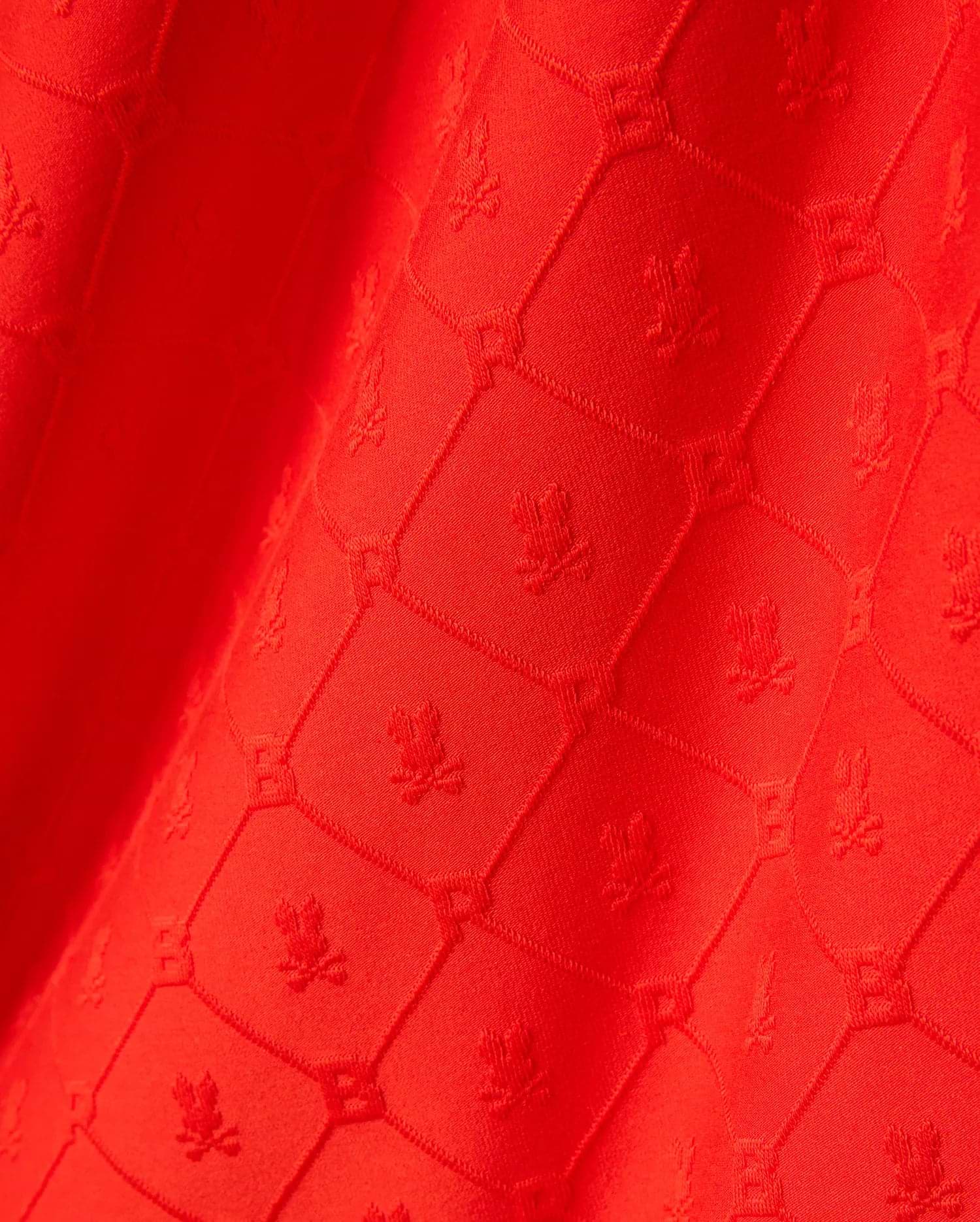 Bright red Mens Garry Relaxed Fit Tee featuring a subtle, all-over tonal jacquard pattern of the iconic Psycho Bunny skull logo within a textured geometric grid.