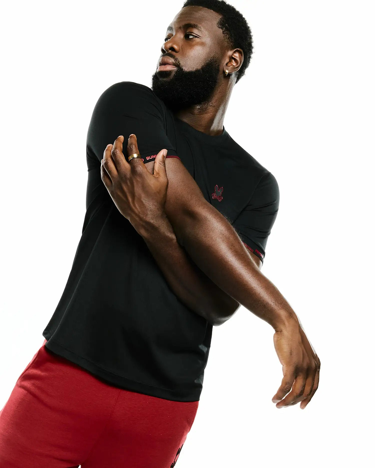 Men's Edmonds Chest Bunny Sport Tee, a black classic fit jersey t-shirt featuring a small red embroidered Psycho Bunny skull logo on the left chest and red Psycho Bunny text on the right sleeve cuff. (3)