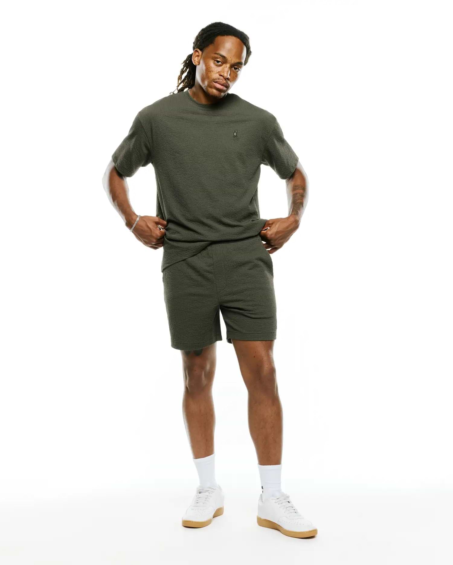 Mens Arlen Relaxed Seersucker Tee in olive green, featuring a textured seersucker fabric and a small embroidered Psycho Bunny skull logo on the left chest, paired with matching seersucker shorts.