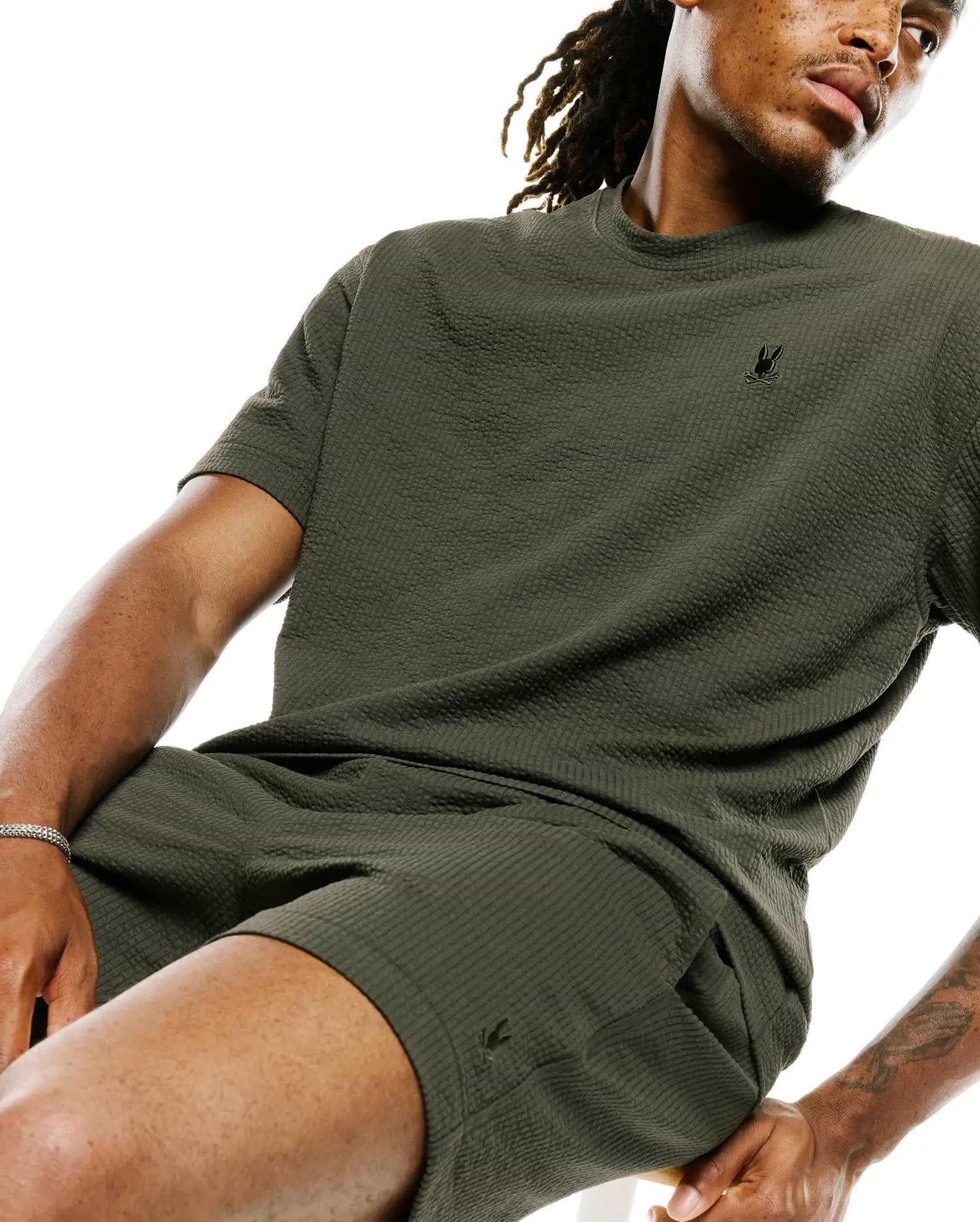 Dark olive green MENS ARLEN RELAXED SEERSUCKER TEE featuring a textured seersucker fabric and a small, embroidered black Psycho Bunny skull logo on the left chest.