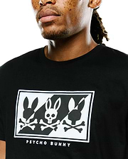 Mens Desmond Graphic Tee, black classic fit jersey, featuring a large chest graphic with three stylized white and black Psycho Bunny skull logos in a checkerboard pattern, bordered by white embroidery and Psycho Bunny text.