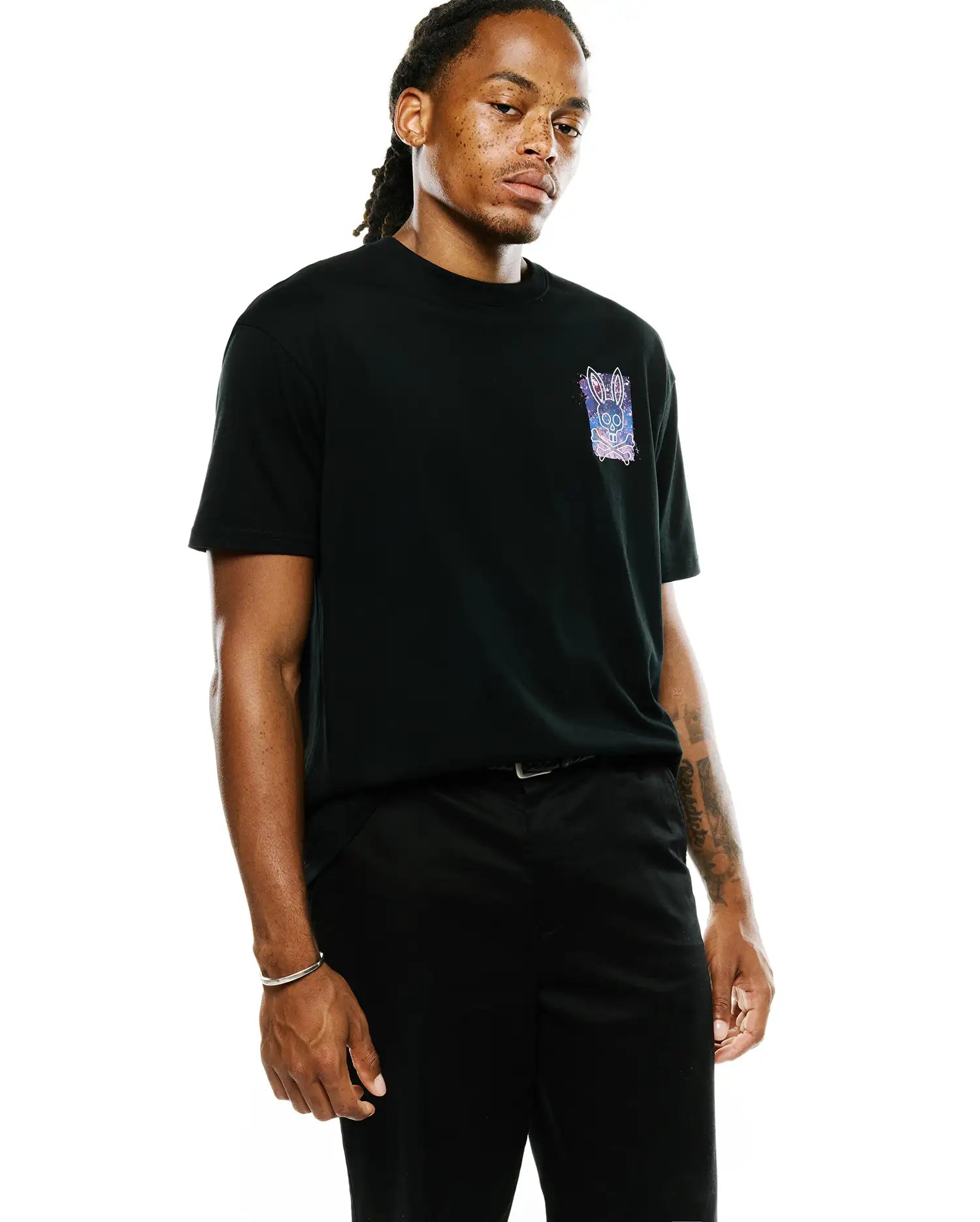Black Mens Isaac Splatter Back Graphic Tee, a classic fit jersey t-shirt featuring a small, vibrant galaxy-inspired purple, blue, pink, and white splatter bunny skull logo with crossbones on the left chest.