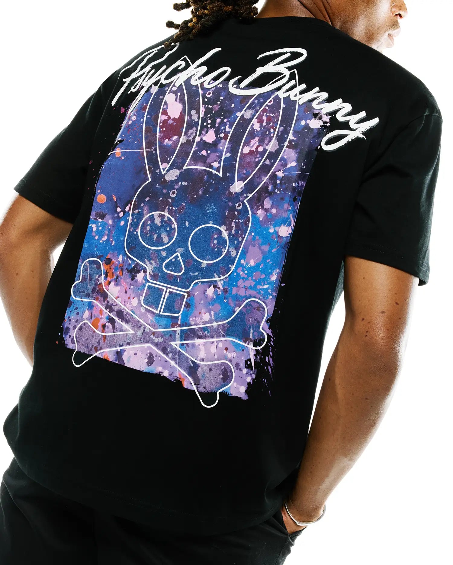 Mens Isaac Splatter Back Graphic Tee, a black t-shirt with a large back graphic: white Psycho Bunny skull and crossbones outline over purple, blue, pink, orange splatter, with white script Psycho Bunny text.