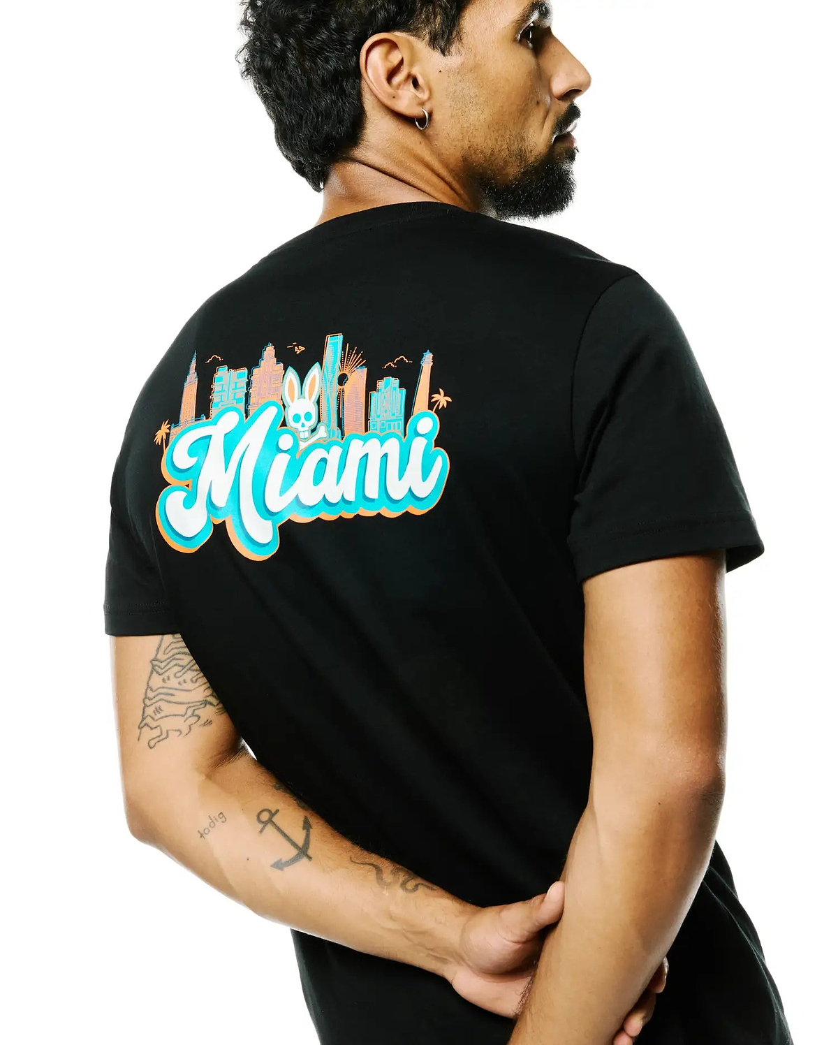 Black Mens Miami Back Graphic Tee, classic fit jersey, featuring a vibrant teal, orange, and white Miami skyline graphic with the Psycho Bunny skull logo on the back. (1)