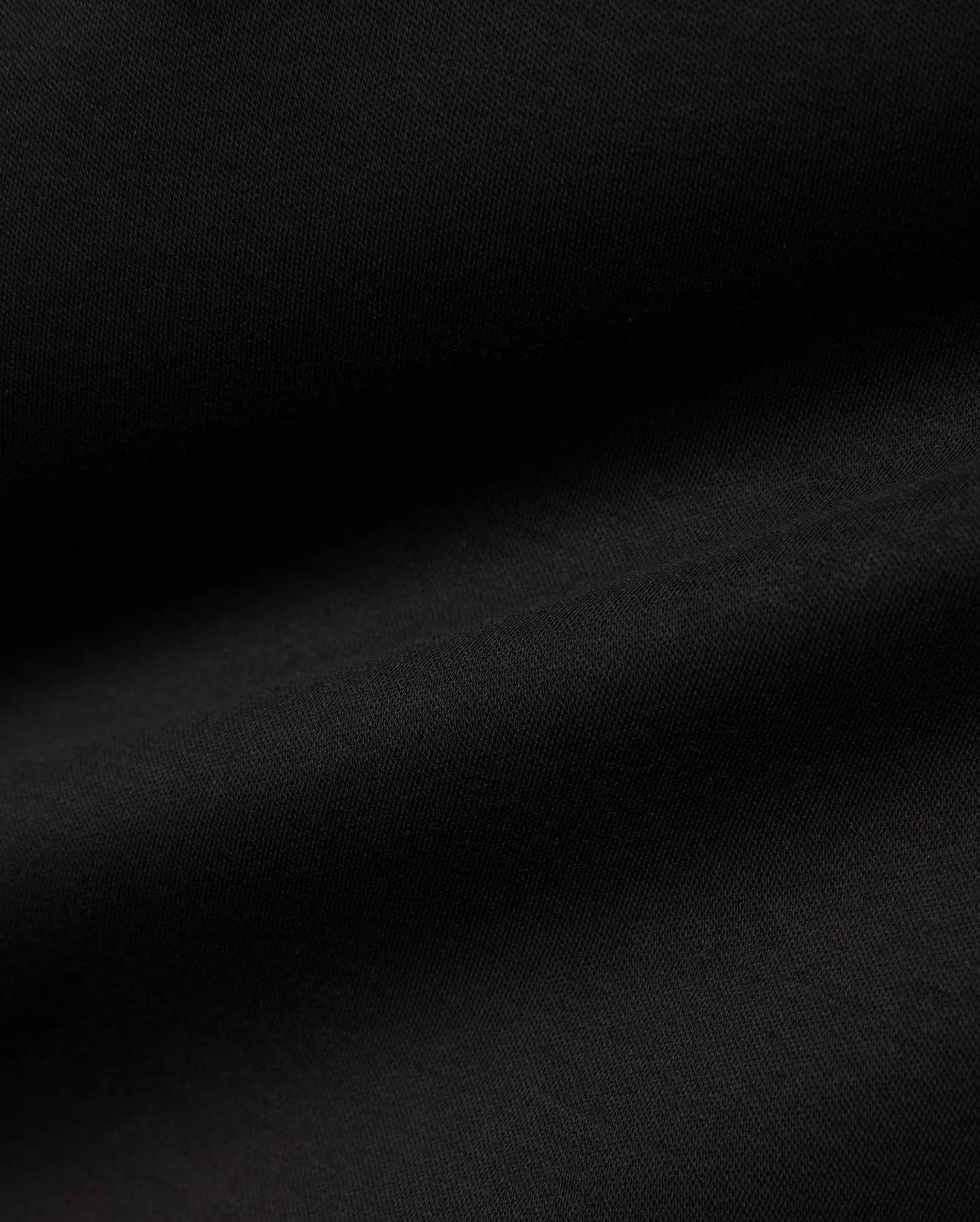 Men's Oscar Longsleeve Tee, a luxurious deep black jersey knit fabric, showcasing a smooth, soft texture with subtle, flowing folds, indicative of premium quality menswear. (6)
