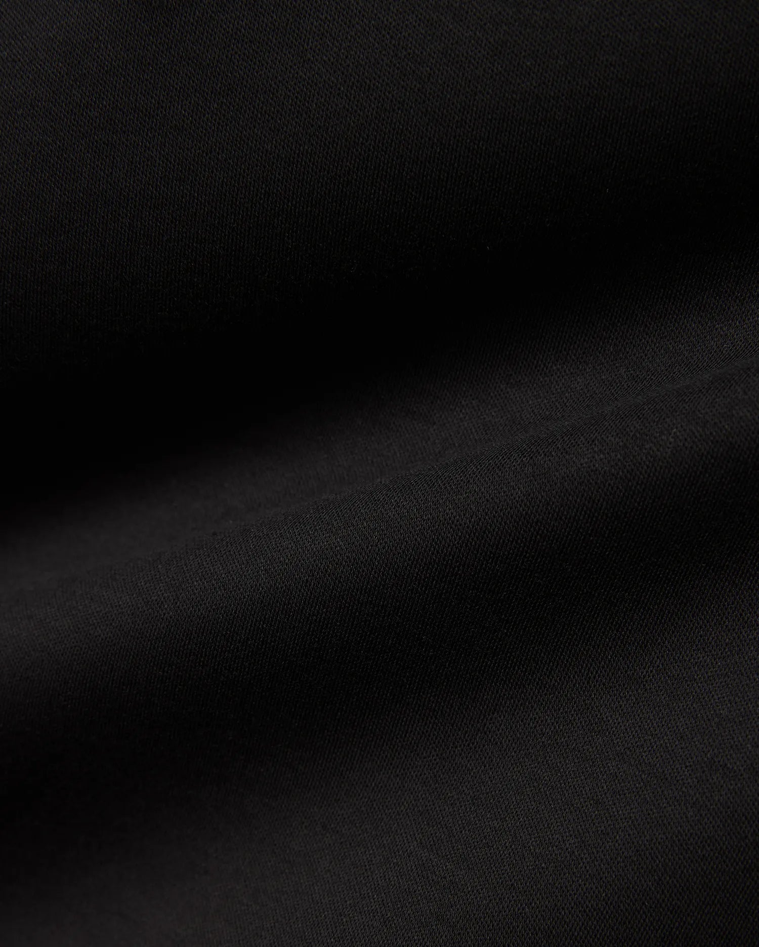 Men's Oscar Longsleeve Tee, a luxurious deep black jersey knit fabric, showcasing a smooth, soft texture with subtle, flowing folds, indicative of premium quality menswear. (6)