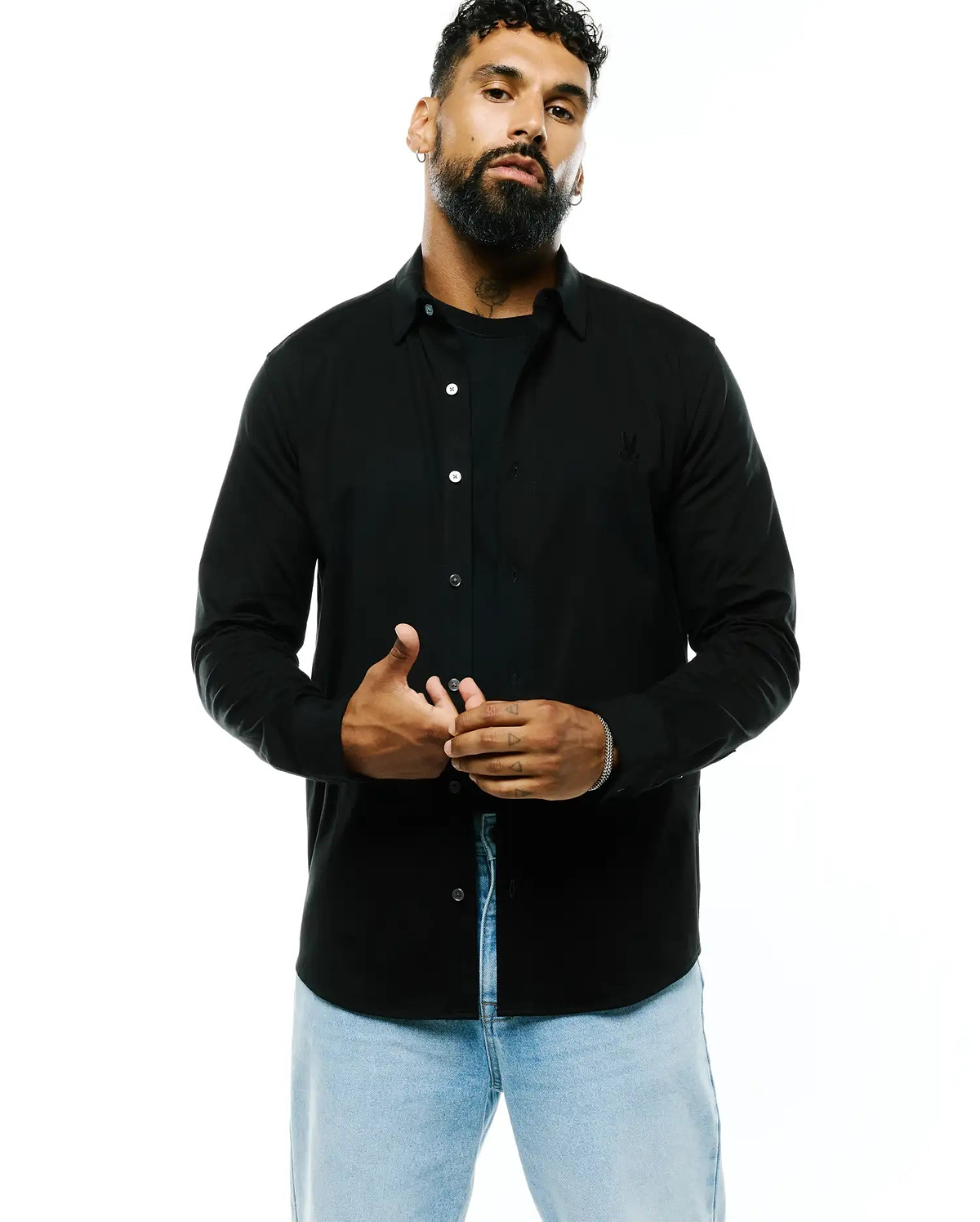 Black Mens Jim Jersey Knit Shirt, a classic fit jersey knit shirt with white buttons and a small embroidered Psycho Bunny skull logo on the left chest.
