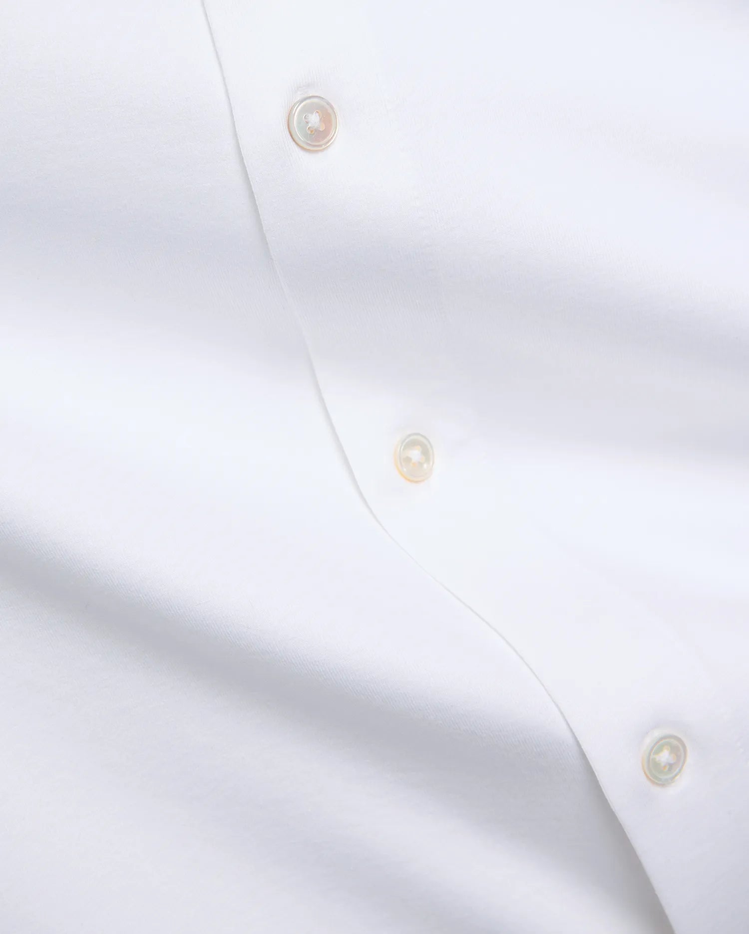 Premium white Jim Jersey Knit Shirt, showcasing a smooth jersey knit fabric and a refined button placket with three iridescent mother-of-pearl buttons. (6)