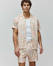Mens Atlas Tencel Shirt, a relaxed fit cream short-sleeve button-up with a vibrant multicolor grid pattern and repeated small Psycho Bunny skull logos.
