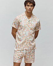 Mens Atlas Tencel Shirt and matching shorts, featuring a relaxed fit, cream base with a wavy multicolor grid pattern, and small repeated Psycho Bunny skull logos throughout.