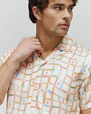 Mens Atlas Tencel Shirt, a relaxed fit, short-sleeved cream shirt with a pastel wavy plaid pattern in pink, blue, green, and orange, featuring small all-over pink Psycho Bunny skull logos.