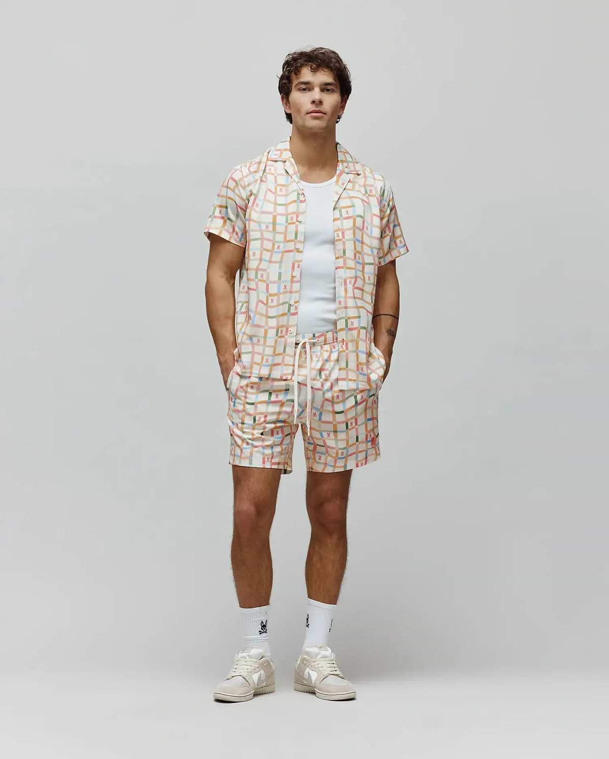 Mens Atlas Tencel Shirt and matching shorts in a relaxed fit, featuring an off-white base with a vibrant multi-colored grid pattern and small repeated Psycho Bunny skull logos.