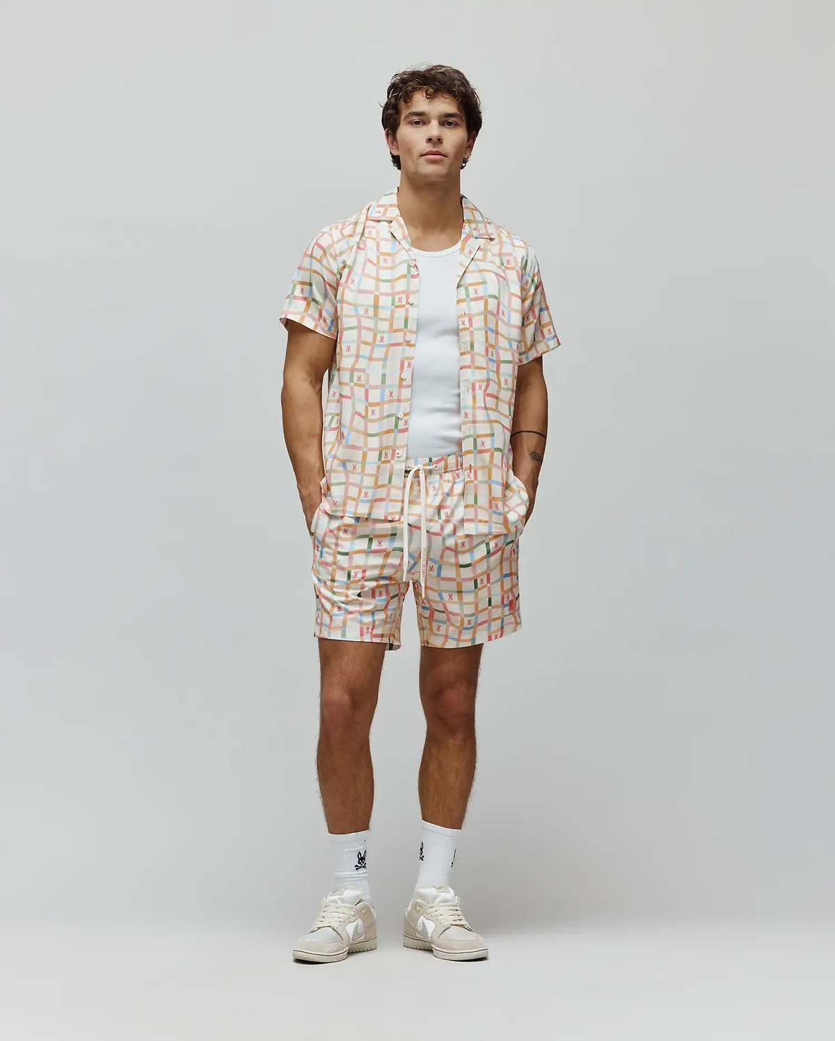 Mens Atlas Tencel Shirt and matching shorts in a relaxed fit, featuring an off-white base with a vibrant multi-colored grid pattern and small repeated Psycho Bunny skull logos.