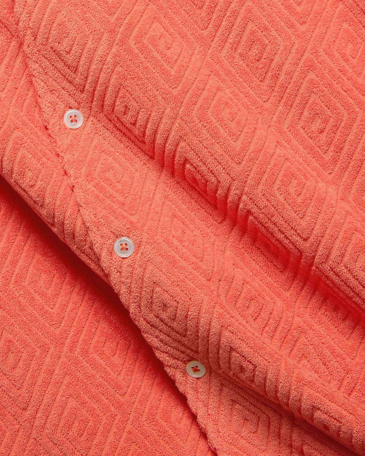 Mens Tristan Shirt, a bold coral plush terry cloth button-up featuring a distinctive raised geometric diamond pattern and contrasting white buttons. (6)