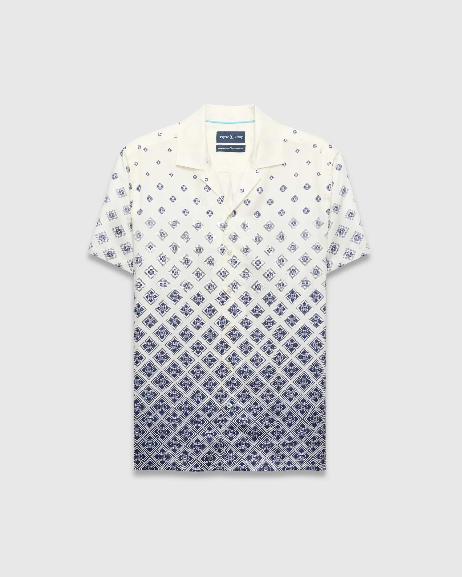 Mens Tobias Tencel Shirt, a relaxed fit cream short-sleeve camp collar shirt with a navy blue diamond pattern that intensifies downwards, featuring the iconic Psycho Bunny skull logo.