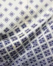 Mens Tobias Tencel Shirt features an off-white smooth Tencel fabric with a repeating navy blue geometric pattern incorporating the iconic Psycho Bunny skull logo throughout, detailed with light buttons.