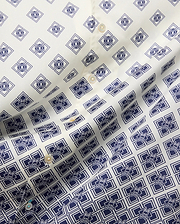 Mens Tobias Tencel Shirt features an off-white smooth Tencel fabric with a repeating navy blue geometric pattern incorporating the iconic Psycho Bunny skull logo throughout, detailed with light buttons.