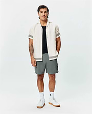 Mens Sunny Linen Shirt, cream, with black zigzag trim on sleeves and hem, paired with grey shorts featuring a small Psycho Bunny logo, white crew socks, and white sneakers. (4)