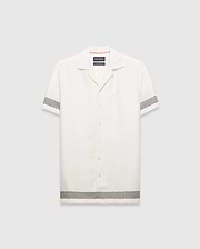 Mens Sunny Linen Shirt, an off-white relaxed linen camp collar shirt, features black zigzag patterns on sleeves and hem, an embroidered Psycho Bunny logo left chest, and orange collar trim. (5)