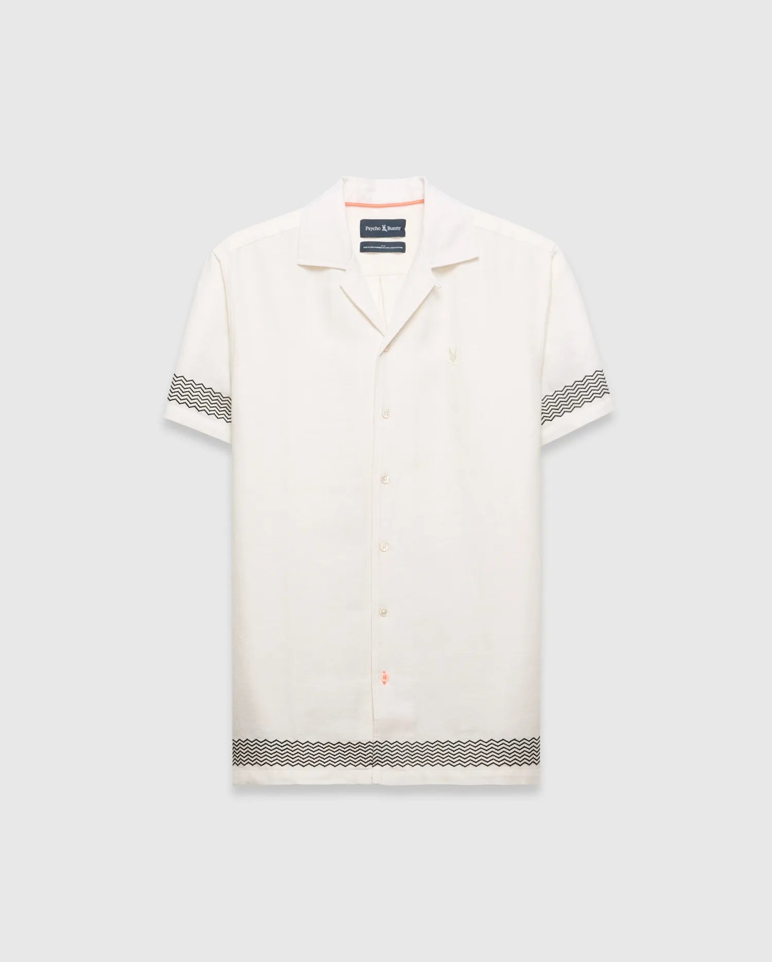 Mens Sunny Linen Shirt, an off-white relaxed linen camp collar shirt, features black zigzag patterns on sleeves and hem, an embroidered Psycho Bunny logo left chest, and orange collar trim. (5)