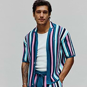 Mens Cliff Shirt, a vibrant knit short-sleeve shirt with teal, pink, light blue, white, and navy vertical stripes, featuring a small embroidered Psycho Bunny skull logo on the left chest. (1)