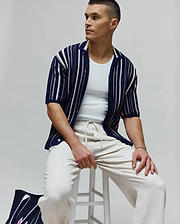 MENS CLIFF SHIRT: Relaxed fit navy knit resort shirt with varied white vertical stripes, featuring a small embroidered Psycho Bunny skull logo on the left sleeve.