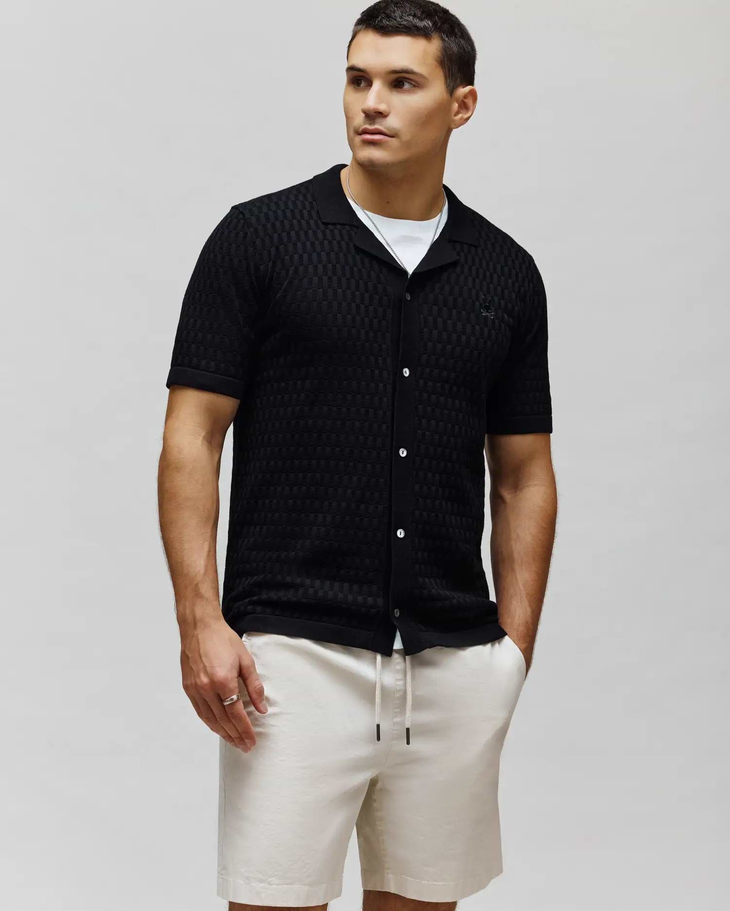 Mens Xandros Knit Shirt, black textured checkerboard knit with a classic fit, spread collar, full white button placket, and a small embroidered Psycho Bunny skull logo on the left chest.