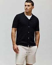 Mens Xandros Knit Shirt, black textured checkerboard knit with a classic fit, spread collar, full white button placket, and a small embroidered Psycho Bunny skull logo on the left chest.