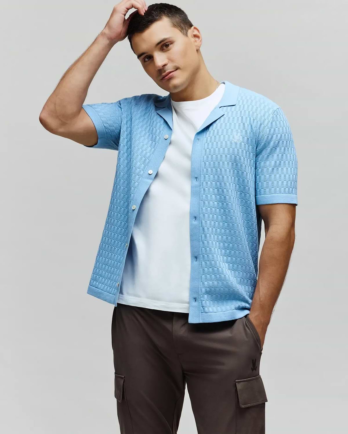 Mens Xandros Knit Shirt in sky blue, featuring a textured checkerboard knit pattern, classic fit, spread collar, full button-front, and a small embroidered Psycho Bunny skull logo on the left chest.