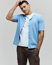 Mens Xandros Knit Shirt in sky blue, featuring a textured checkerboard knit pattern, classic fit, spread collar, full button-front, and a small embroidered Psycho Bunny skull logo on the left chest.