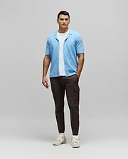 Mens Xandros Knit Shirt, a light blue relaxed-fit knit shirt with a textured woven pattern, open collar, and small embroidered Psycho Bunny skull logo on the left chest.
