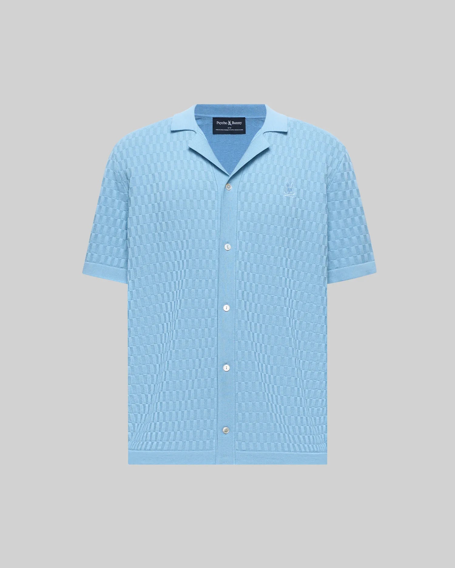 Mens Xandros Knit Shirt, light blue with a checkerboard knit pattern, featuring a spread collar, short sleeves, full button-front, and a small embroidered Psycho Bunny skull logo on the left chest.
