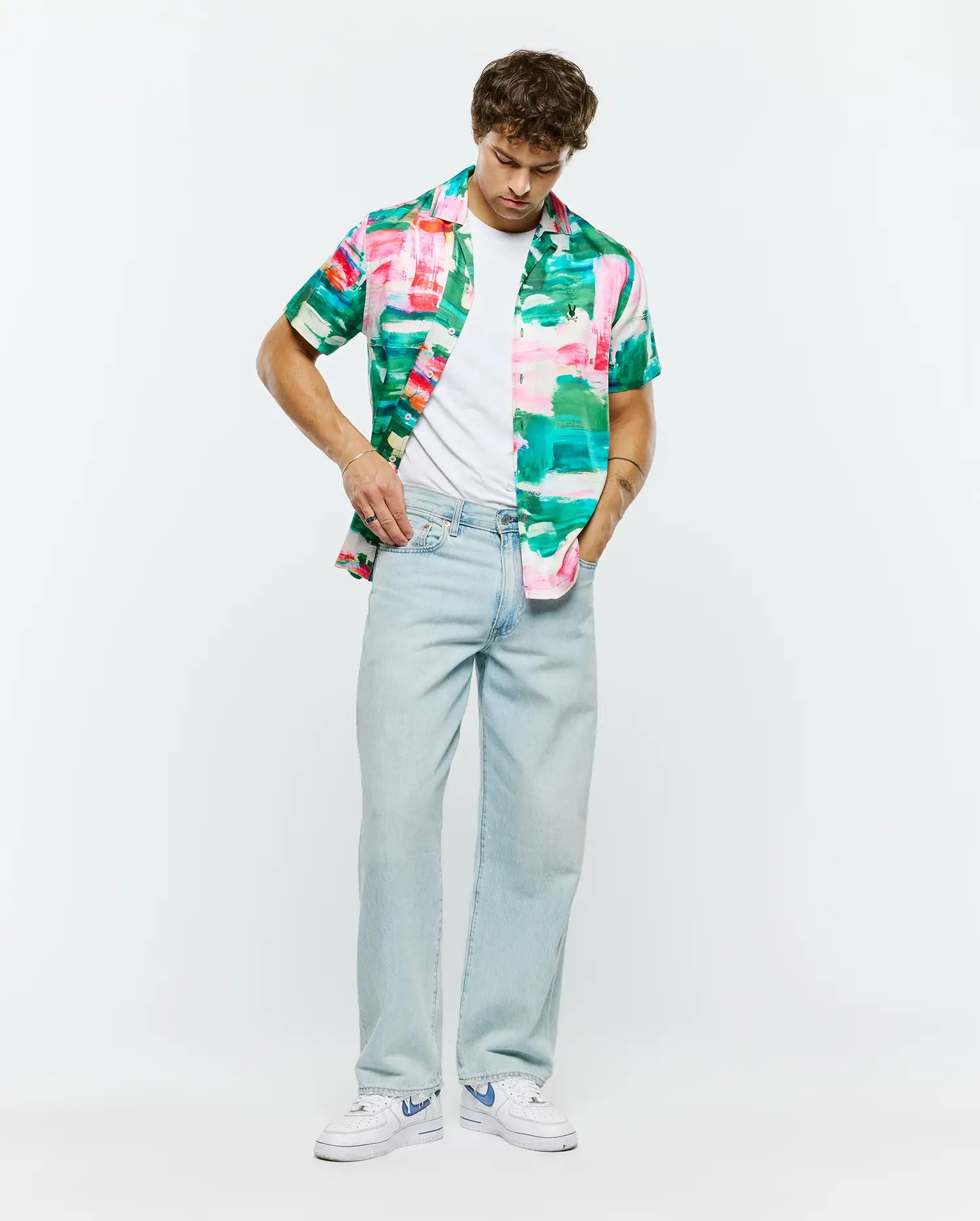 Psycho Bunny Mens Nate Tencel Shirt, a relaxed fit short-sleeve button-up with a vibrant abstract brushstroke pattern in pink, green, teal, and white, embodying refined streetwear.