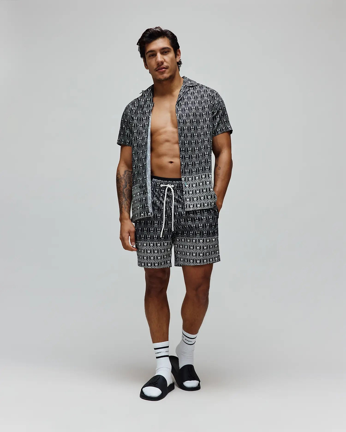 Mens Keon Tencel Shirt, a relaxed fit black Tencel short-sleeve shirt, and matching shorts, both featuring a white all-over Psycho Bunny skull logo pattern and white drawstrings. (3)