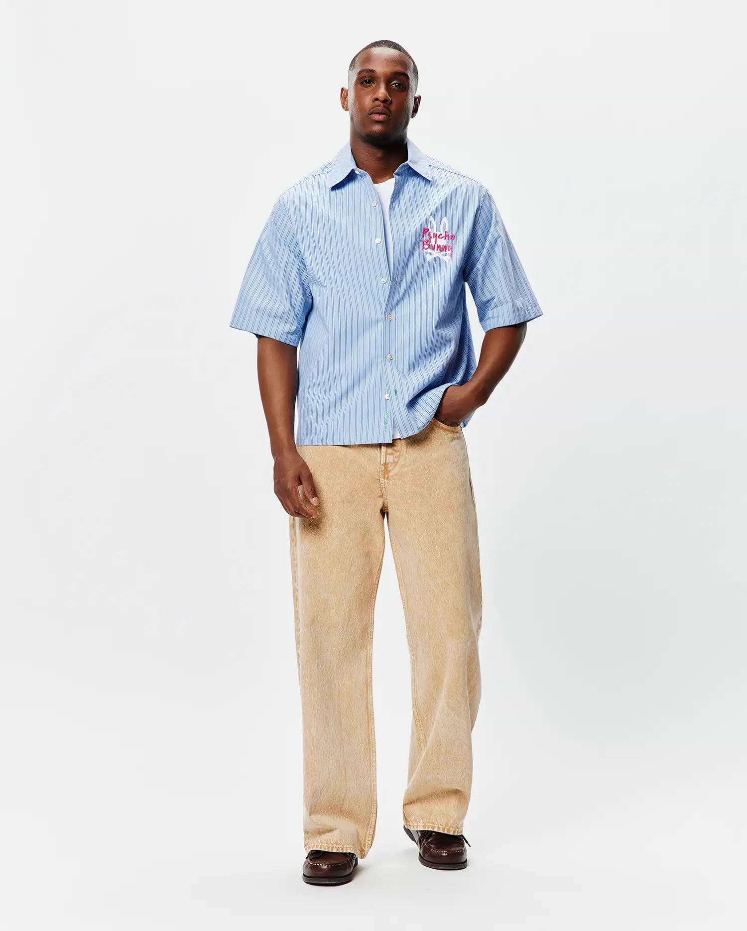 Mens Duncan Stripe Shirt, a light blue relaxed fit short-sleeve button-up with thin dark vertical stripes and an embroidered hot pink Psycho Bunny skull logo on the left chest. (5)